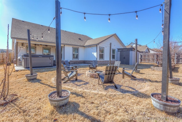 back of house featuring a fire pit, a hot tub, and a storage unit