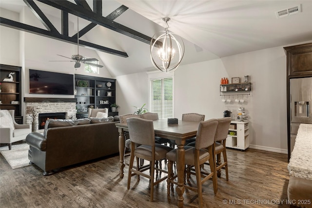 dining space featuring ceiling fan with notable chandelier, a fireplace, lofted ceiling with beams, and dark hardwood / wood-style floors