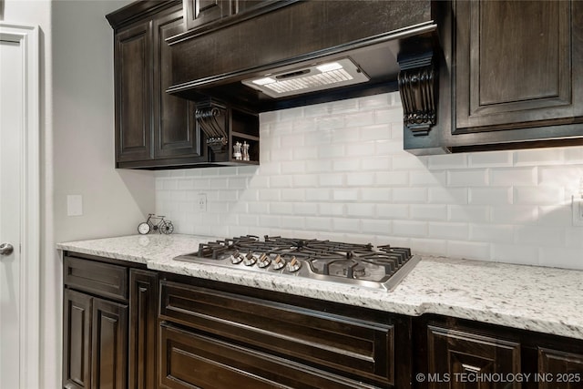 kitchen with dark brown cabinetry, decorative backsplash, custom range hood, and stainless steel gas stovetop