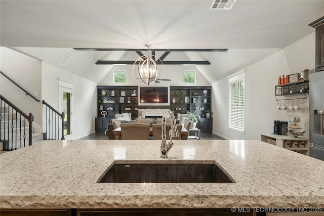 kitchen featuring a fireplace, decorative light fixtures, sink, a chandelier, and light stone countertops