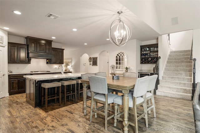 dining area with wood-type flooring, sink, and a chandelier