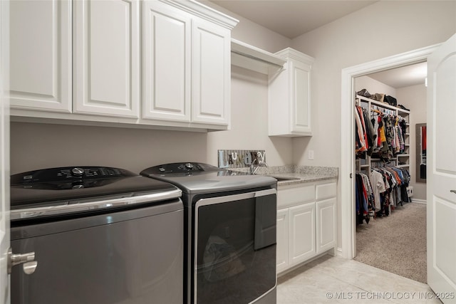 laundry area featuring cabinets, sink, light carpet, and washer and clothes dryer