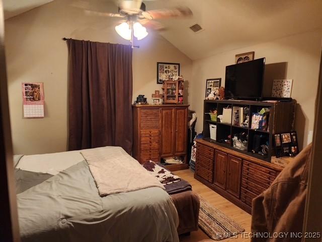 bedroom with ceiling fan, lofted ceiling, and light hardwood / wood-style flooring