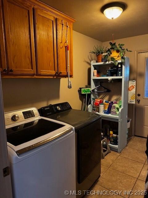 laundry room featuring cabinets, light tile patterned floors, and independent washer and dryer