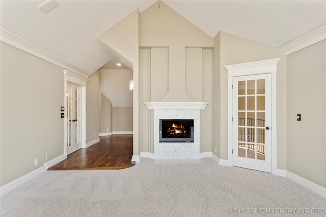 unfurnished living room featuring vaulted ceiling, a tile fireplace, french doors, and carpet