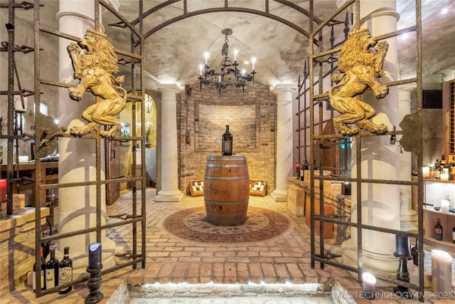 wine room featuring decorative columns and an inviting chandelier