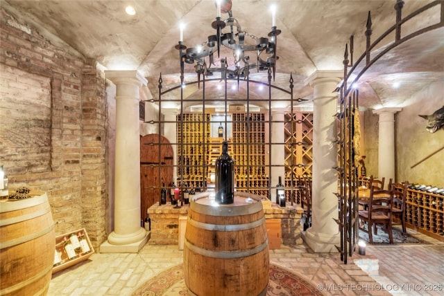 wine room with decorative columns, vaulted ceiling, and a chandelier