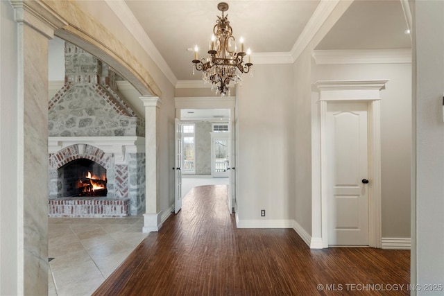 corridor featuring hardwood / wood-style flooring, ornamental molding, a chandelier, and ornate columns