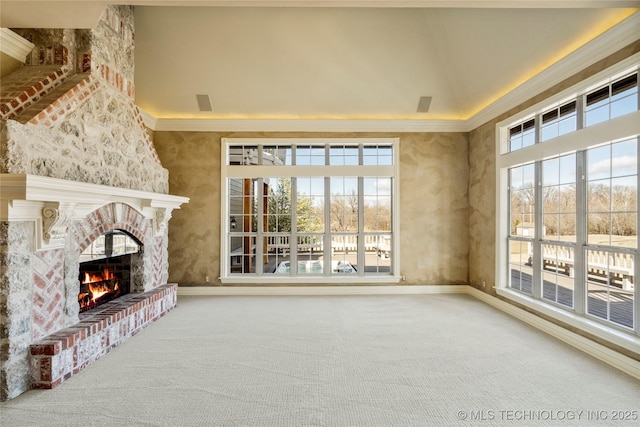 unfurnished living room with a brick fireplace, ornamental molding, a healthy amount of sunlight, and carpet