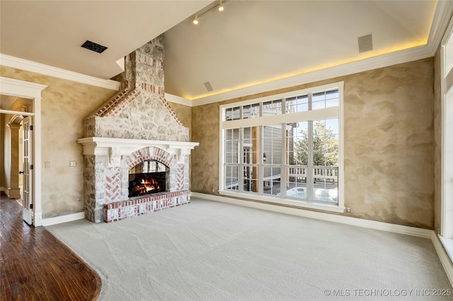 unfurnished living room featuring vaulted ceiling, crown molding, a brick fireplace, and carpet