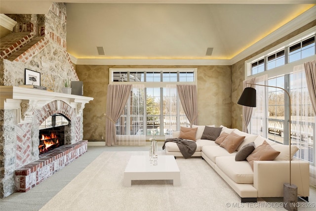 carpeted living room featuring crown molding, a towering ceiling, and a fireplace