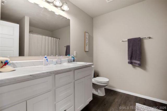 bathroom with toilet, vanity, wood finished floors, a shower with curtain, and baseboards