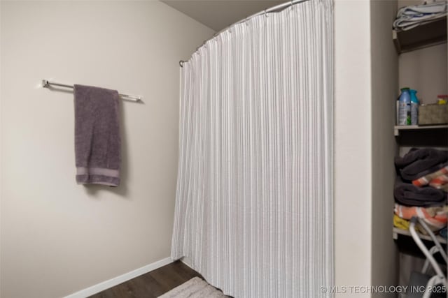 bathroom with baseboards, wood finished floors, and a shower with shower curtain