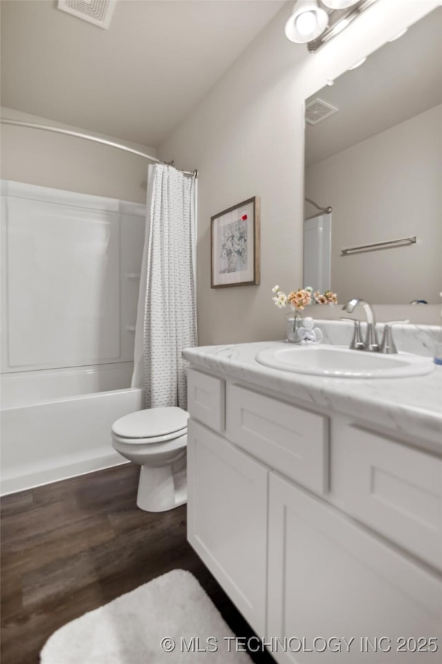 full bathroom featuring toilet, wood finished floors, vanity, visible vents, and shower / tub combo with curtain