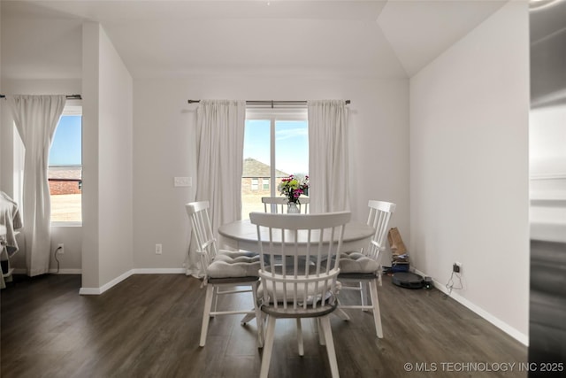 dining area with vaulted ceiling, dark wood-type flooring, and baseboards