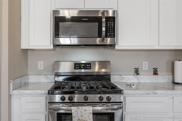 kitchen with appliances with stainless steel finishes, white cabinetry, and light stone countertops