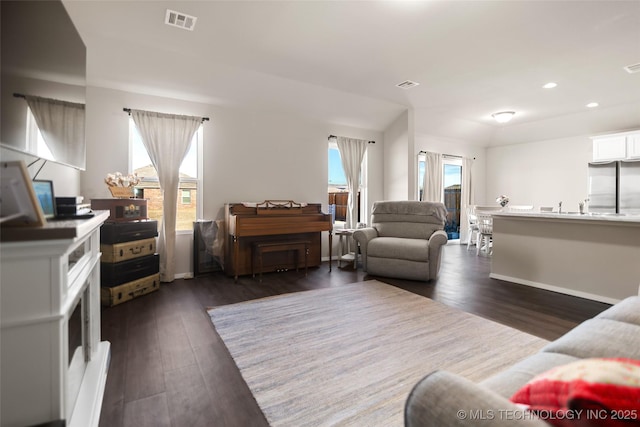 living room featuring dark wood-style flooring, visible vents, and recessed lighting