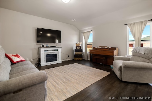 living room with dark wood-style floors, lofted ceiling, a wealth of natural light, and visible vents