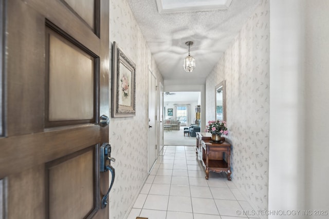 corridor featuring a notable chandelier, a textured ceiling, and light tile patterned flooring