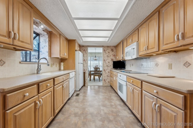 kitchen with white appliances, sink, and backsplash