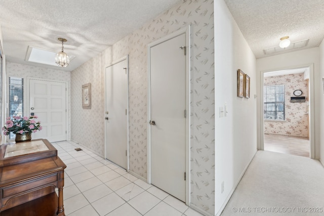 foyer entrance featuring light tile patterned floors, a notable chandelier, and a textured ceiling