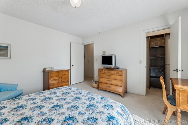 carpeted bedroom featuring a spacious closet and a textured ceiling