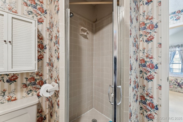 bathroom featuring a shower with shower door and toilet