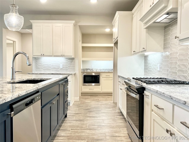 kitchen featuring white cabinetry, stainless steel appliances, range hood, and sink