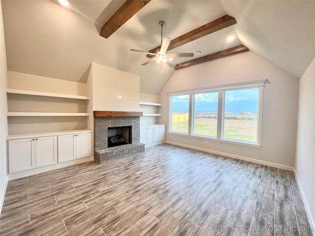 unfurnished living room with ceiling fan, a brick fireplace, lofted ceiling with beams, and light hardwood / wood-style flooring