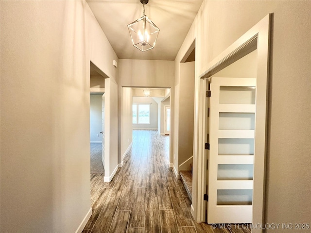 hallway with an inviting chandelier, wood-type flooring, and built in features