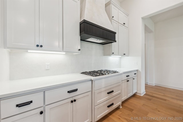 2722 E 134th Cir, Bixby, OK 74008 - kitchen with premium range hood, stainless steel gas stovetop, backsplash, light wood-type flooring, and white cabinets