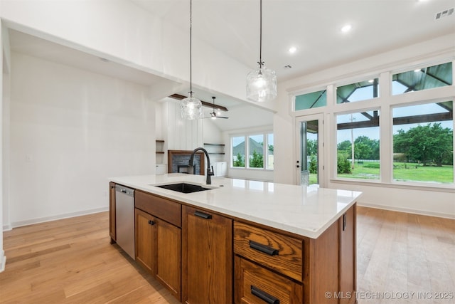 2722 E 134th Cir, Bixby, OK 74008 - kitchen with dishwasher, a fireplace, brown cabinetry, light wood-style floors, and pendant lighting