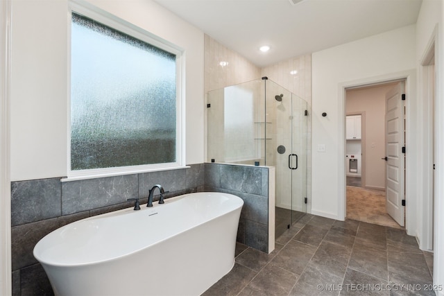 2722 E 134th Cir, Bixby, OK 74008 - bathroom featuring plenty of natural light, a freestanding bath, a stall shower, recessed lighting, and stone finish flooring