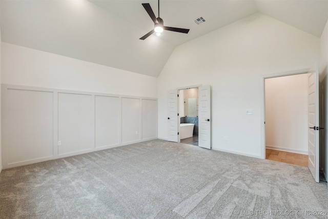 2722 E 134th Cir, Bixby, OK 74008 - unfurnished bedroom featuring carpet floors, high vaulted ceiling, ensuite bath, a ceiling fan, and a decorative wall