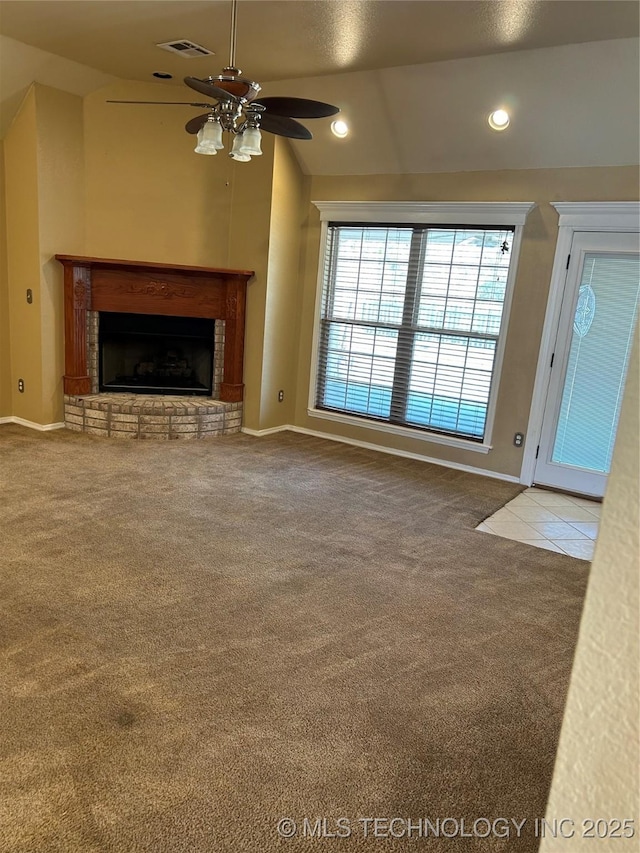 unfurnished living room featuring ceiling fan, a brick fireplace, vaulted ceiling, and light carpet