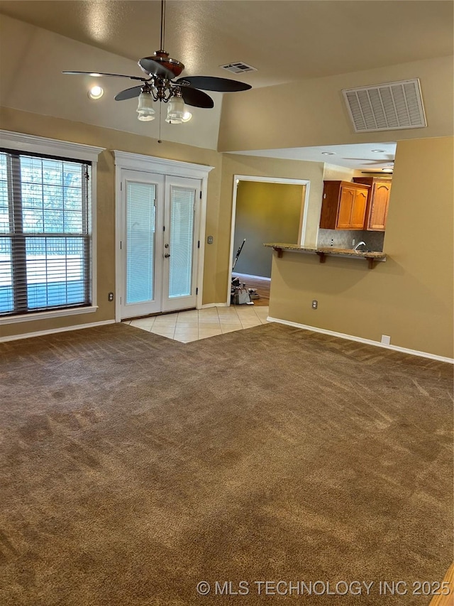 unfurnished living room with vaulted ceiling, light carpet, ceiling fan, and french doors