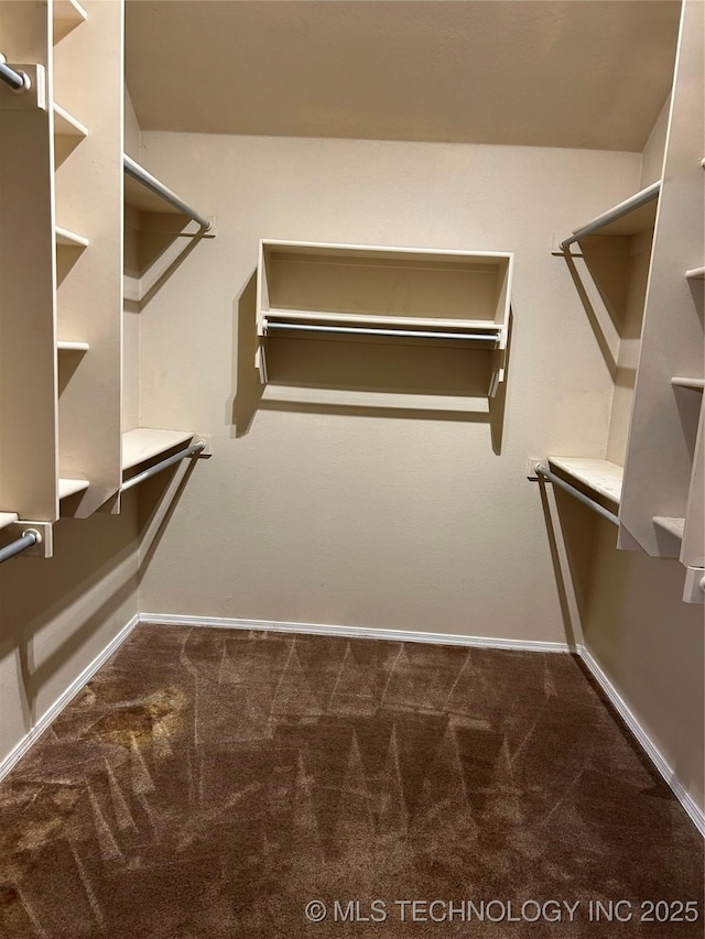 walk in closet with dark carpet