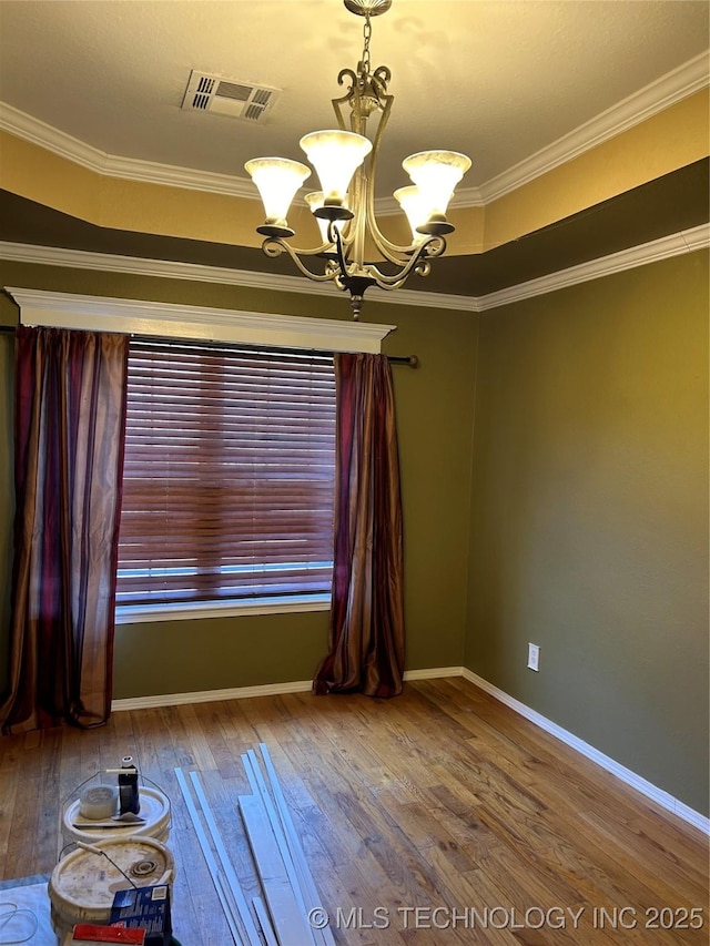 spare room with a notable chandelier, crown molding, wood-type flooring, and a raised ceiling