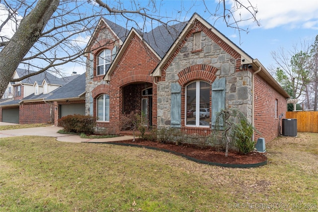 view of front of home with a garage, a front yard, and central air condition unit