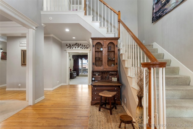 stairs featuring hardwood / wood-style flooring, ornamental molding, and a towering ceiling