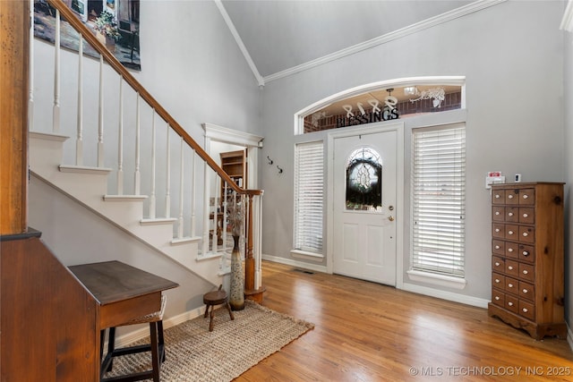 entrance foyer with crown molding, high vaulted ceiling, and hardwood / wood-style flooring