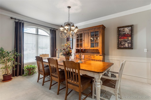 dining room featuring light colored carpet, ornamental molding, and a chandelier