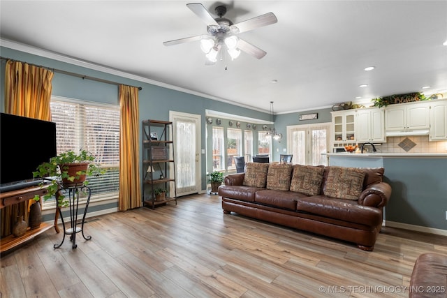 living room with ceiling fan, ornamental molding, and light wood-type flooring