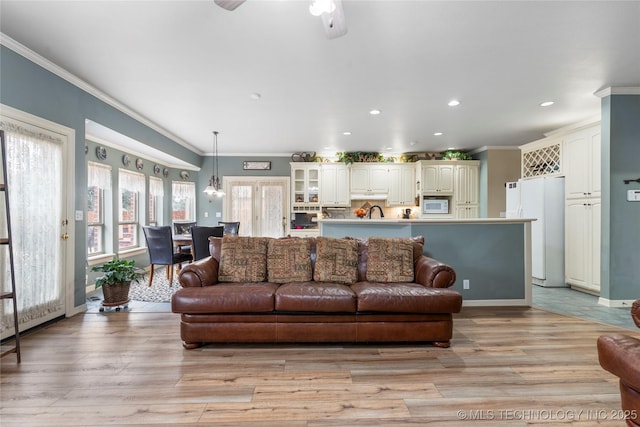 living room featuring crown molding, ceiling fan, and light hardwood / wood-style flooring