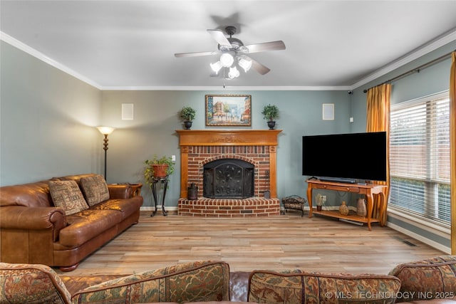 living room featuring crown molding, a brick fireplace, ceiling fan, and light hardwood / wood-style flooring