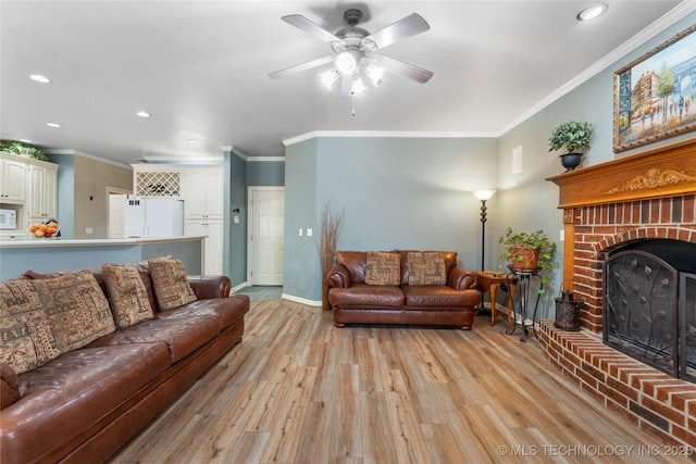 living room featuring ceiling fan, ornamental molding, light hardwood / wood-style floors, and a brick fireplace