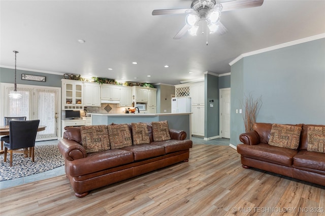 living room with crown molding, ceiling fan, and light hardwood / wood-style floors