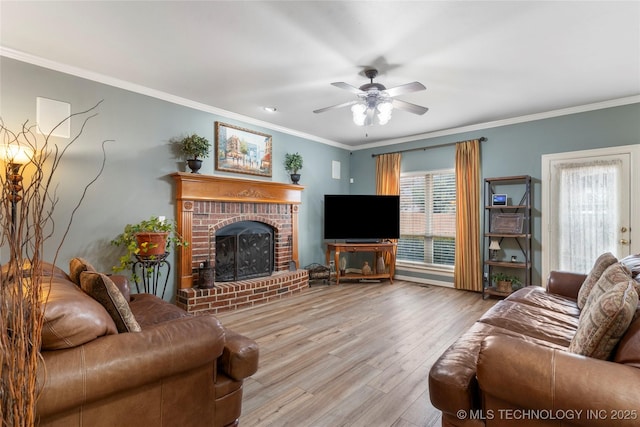 living room with a brick fireplace, crown molding, light hardwood / wood-style flooring, and ceiling fan