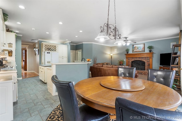 dining space with crown molding, ceiling fan, and a fireplace