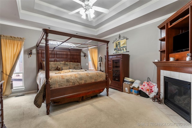 bedroom featuring light colored carpet, ornamental molding, a tile fireplace, and a raised ceiling